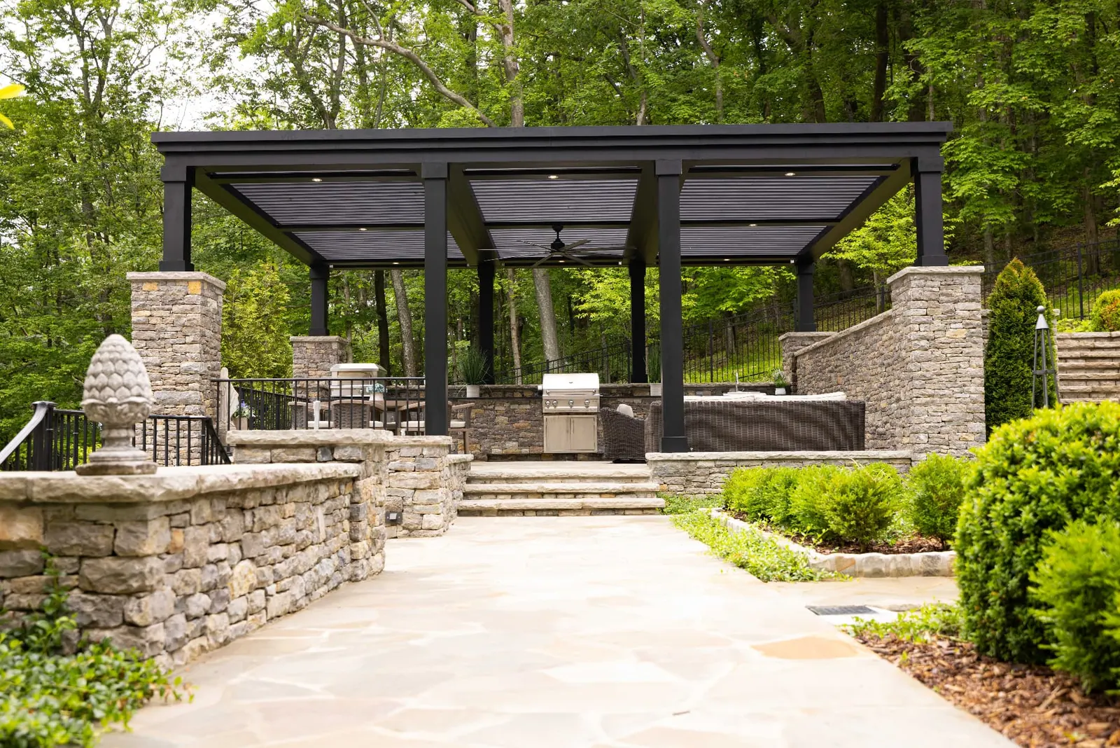 Dark pergola integrated into terraced stone landscaping