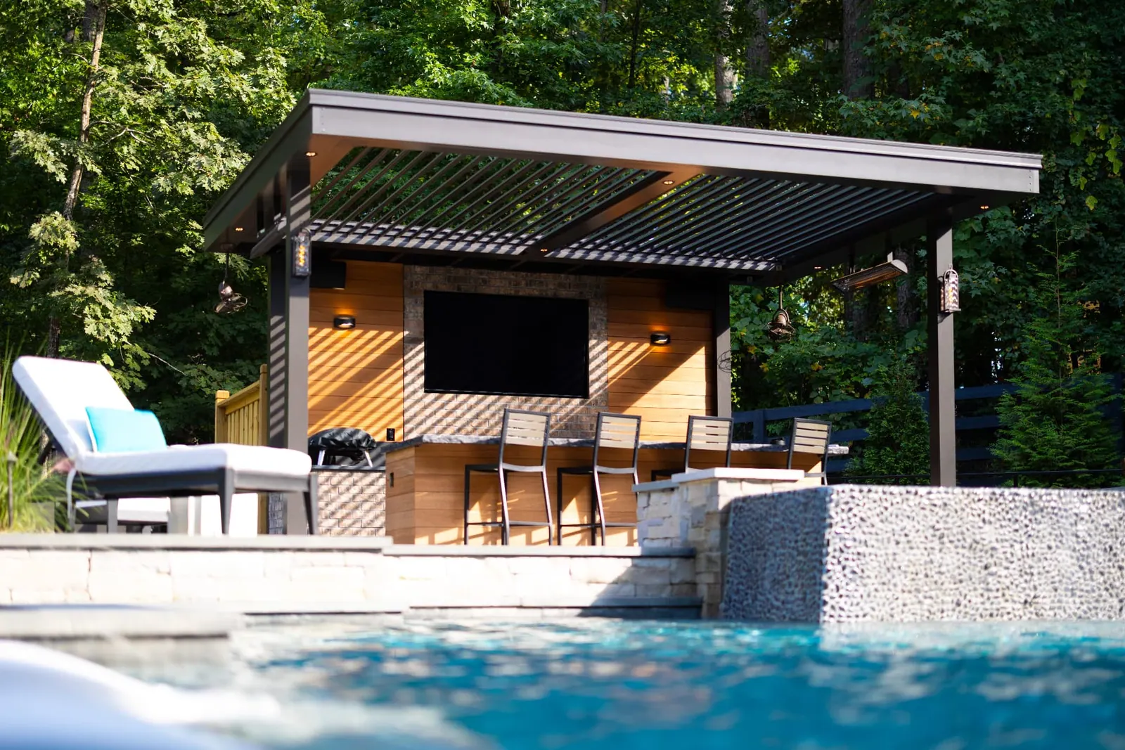Modern louvered pergola covering a poolside bar and television