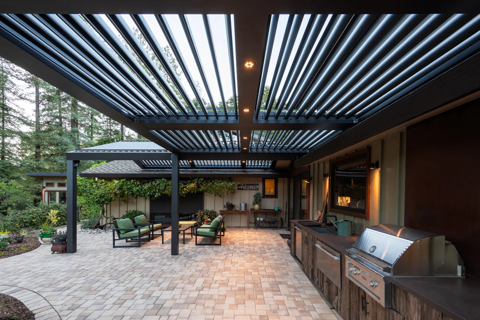 Large louvered pergola covering an outdoor kitchen and patio seating area